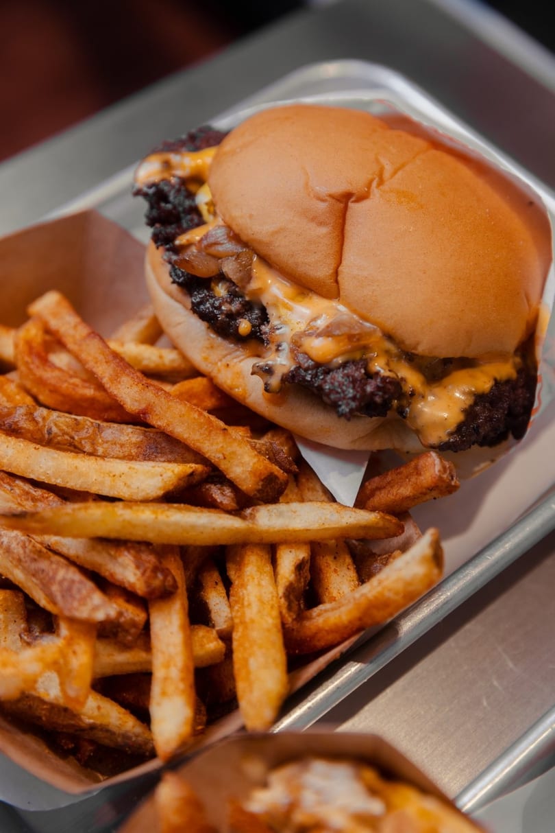 Cheeseburger with caramelized onions and melted cheese, served with a side of seasoned french fries.