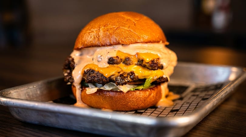 A double smash burger with melted cheese, lettuce, and special sauce on a brioche bun.