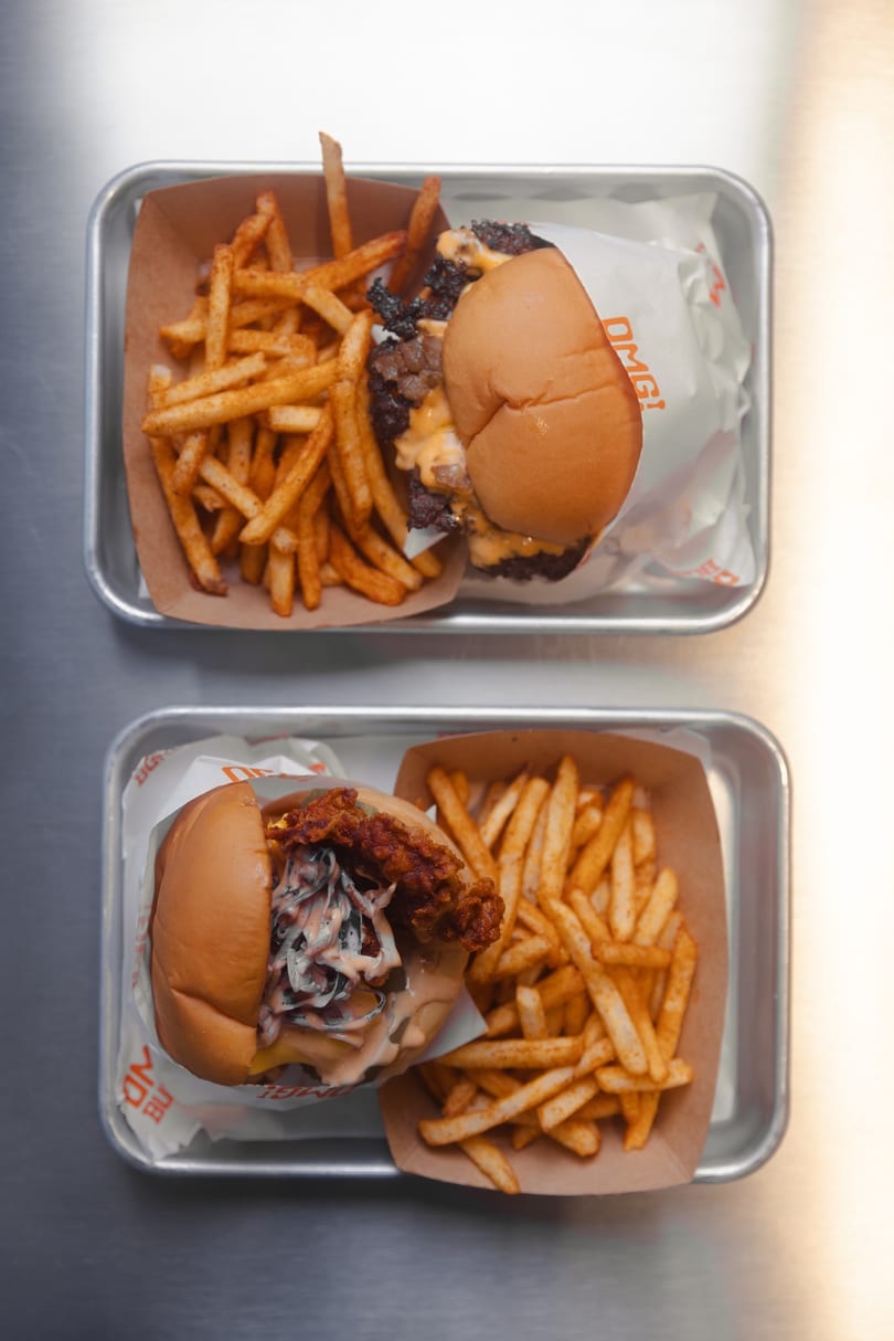Two trays of burgers and fries, one with a beef burger, the other a fried chicken burger.