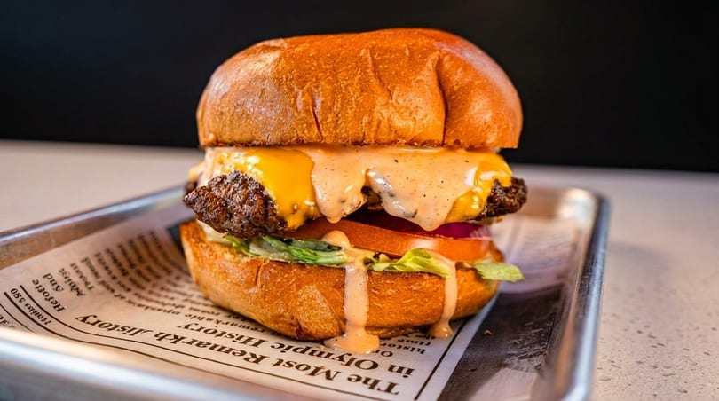 Cheeseburger with melted cheese, special sauce, lettuce, tomato, and onion on a bun.